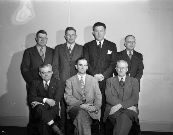 Seven members of the newly elected Madison City Council pose for a group portrait in the city manager's office. Front row, left to right: Franz C. Haas, William C. Sachtjen, and Harrison L. Garner. Rear row, left to right: John E. Coyne, Henry E. Reynolds, Ted C. Boyle, and Peter C. Lynaugh. Reynolds would go on to be mayor of Madison from 1961 to 1965.