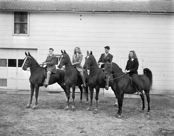 Four University of Wisconsin students on their horses at the Hoofers' Club horse show at the University of Wisconsin-Madison Stock Pavilion. From left are Eugene Osborn, Patricia Jane Ewell, Robert M. Hensley and Mary Immell.