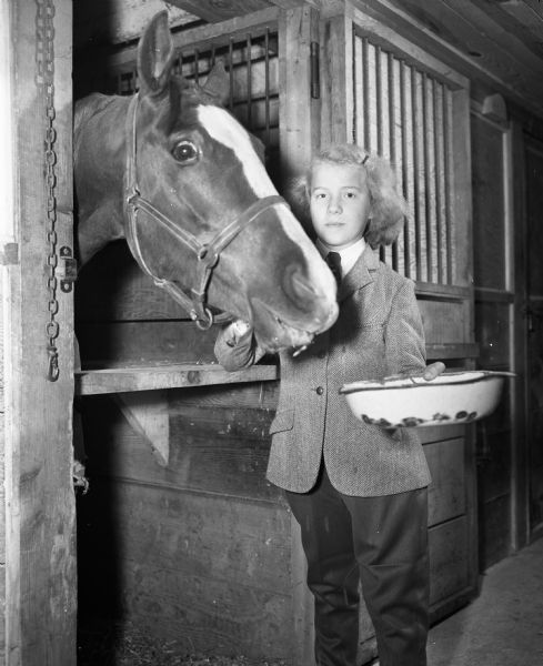 Lois Jean Klinke, 10-years-old, daughter of Maurice and Trudy Klinke, 3255 Monona Drive, feeding her horse at the University of Wisconsin-Madison Hoofers' Club horse show at the Stock Pavilion.