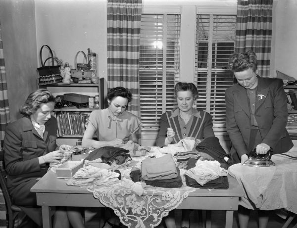 Members of the Shorewood Hills Community League sorting clothing collected for the Quaker Relief Organization. From left are: Mrs. Harold R. (Hjordis) Wolfe, Mrs. C. Harvey (Emma) Sorum, Mrs. Richard (Mildred) Campbell, and Mrs. Harry W. (Cath.) King.