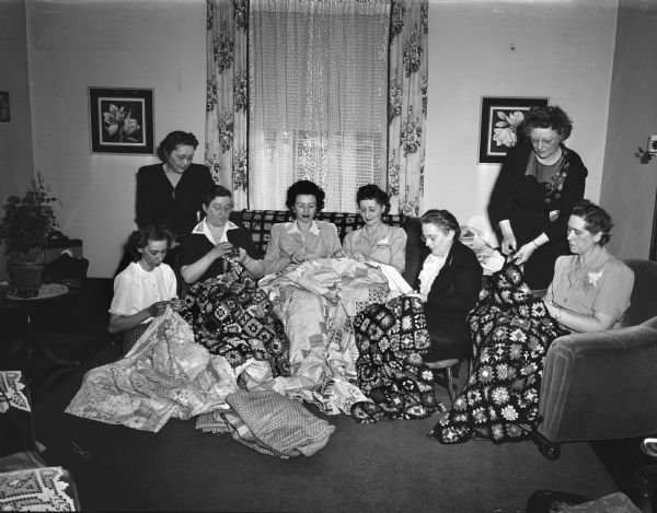 Group portrait of members of the Children's Convalescent Service Club shown making afghans and quilts for rheumatic fever patients. Left to right: Mmes. R. Houtler, A. Schmitt, F.A. Tesar, M. Erickson, C. Leahy, George Howe, Theo C. Raymond and E.C. Thale.