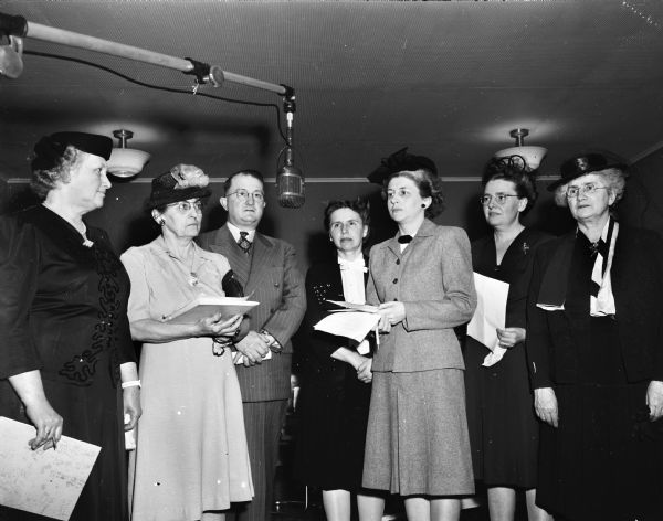 Group portrait of leaders of the Dane County Cancer Fund Drive as they prepare to broadcast a radio appeal for support. Pictured left to right; Mrs. Jesse Uphoff, Cottage Grove; Mrs. David C. Anthony, Brooklyn; Alex Miller, Verona; Mrs. Monroe Tubbs, Cross Plains; Mrs. Roman Esser, Cross Plais; Mrs. Ralph Jacobs, Verona, and Mrs. George Ritter, Madison.
