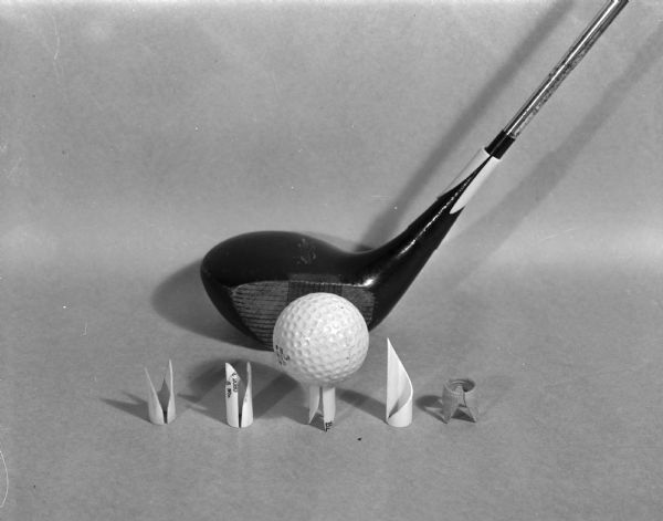Several patented golf tees designed to slip over the handle of a golf club. Shown are two different types of two-pronged tees, a three-pronged tee, a single-pronged, and another type. The designer is M.C. "Pete" Pierce, 115 South Brooks Street, and the tees are named Novel-Tee.