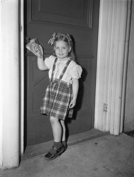 Connie Wear, 332 Lakewood Boulevard, hanging a bright green May Basket that she made in Marjorie Deakman's nursery school, Lakewood.