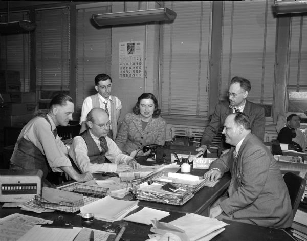 Editorial staff of the <i>Wisconsin State Journal</i> gathered around a table. L to R: Harold McClelland, State Editor; (sitting) Lawrence Fitzpatrick, City Editor; (standing) Joseph Caposella; (woman) Louise Marston, Society Editor; (standing) William Doudna, News Editor; (sitting) Henry McCormick (?), sports Editor.