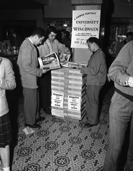 Display of <i>Esquire</i> magazines in a store. The June 1947 issue has a feature article on the University of Wisconsin. Several students are looking at copies.