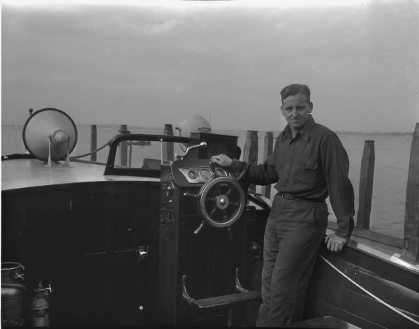 Captain Harvey Black, veteran chief lifeguard of the University of Wisconsin-Madison lifeguards, standing in his boat, "Isabel II".