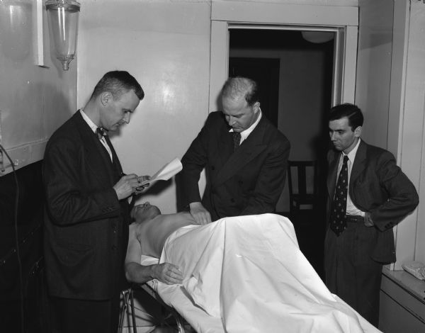 Three doctors examining a patient for the Cancer Society.