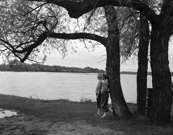 Jane and Jone Johnson, daughters of Mr. and Mrs. Lester Johnson of Black River Falls, standing beside Lake Wingra at Vilas Park.