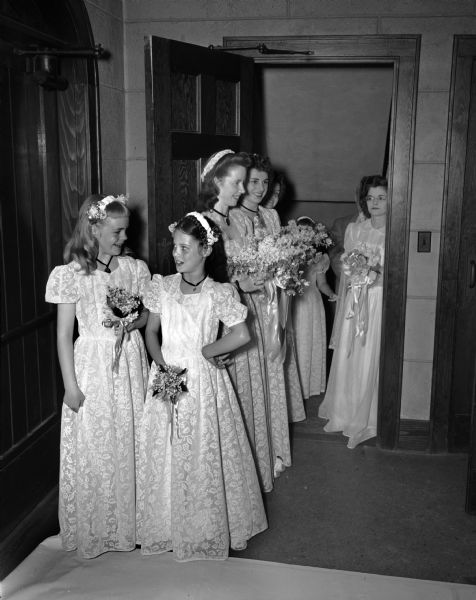 The wedding procession of Jane Morris including the bride, flower girl, maid of honor, two bridesmaids, and two junior bridesmaids at St. Andrew's Episcopal Church.