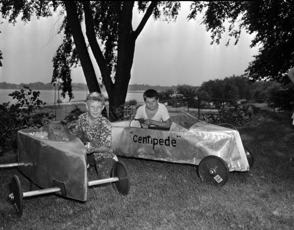 Pierre Slightam, age 13, left, and his brother, Warren, age 11, 427 West Wilson Street, are putting the finishing touches on their Soap Box Derby racers. The two brothers will be competing for the city championship the following Sunday. Pierre races in Class A and Warren in Class B.