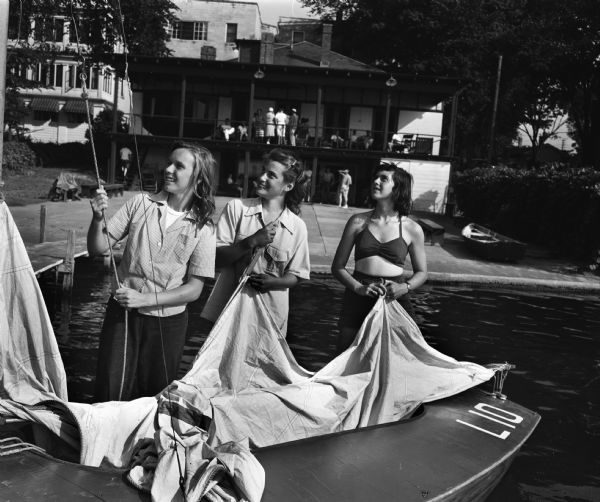 Mendota Yacht Club members taking down the sail from their boat, "The Freckles," on the pier behind the James Payton house, 409 N. Blair Street. Left to right: Rosamond Ross, Ann Hastings, and Gina Johnson.