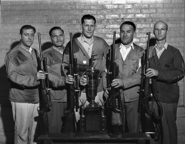 Group portrait of five men with rifles and Hearst trophy.