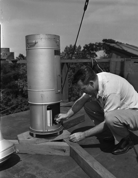George R. Jenkins, assistant meteorologist, checking rain gauge on the roof of North Hall on University of Wisconsin-Madison Campus.  The station started after 1853 when the Smithsonian Institution offered to furnish equipment for weather observations.