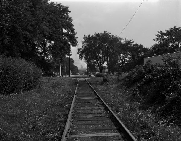 The train engineer's view (looking east) of the Illinois Central Railroad crossing at Regent Street, Breeze Terrace, and Little Street, taken one-hundred feet west of Breeze Terrace. In the distance is the Wisconsin State Capitol. The engineer has no view of the crossing until the train reaches it. The traffic has no view of the railroad track until the train appears.
