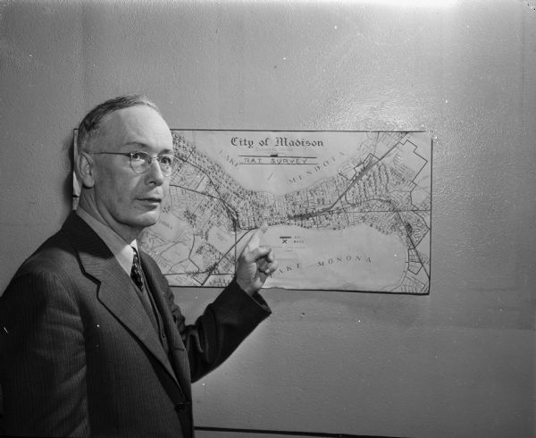 James L. Clark, Madison city health inspector, shown pointing to a map of Madison marked with X's signifying places with rat infestation.