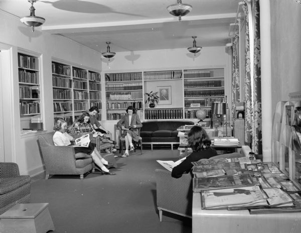 Five women enjoying the library at Elizabeth Waters Dormitory on the University of Wisconsin-Madison campus. The portrait on the wall at the far end is of Elizabeth Waters, regent for whom the building was named.
