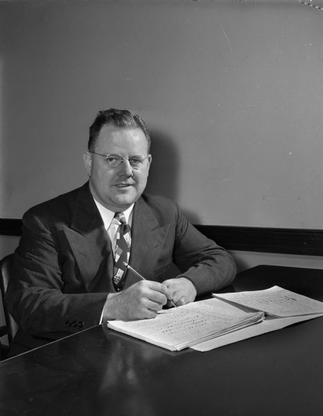 Glenn F. Olwell, Industrial Coordinator of the Vocational and Adult Education School, 211 South Carroll Street, seated at his desk.