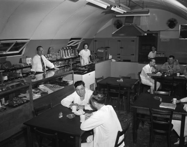 Workers and patients at tables in the canteen in a Quonset hut at the Veterans Administration Hospital on the grounds of the Mendota State Hospital.