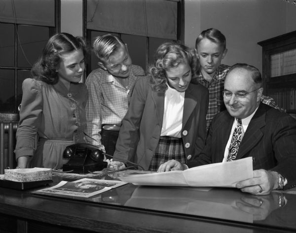 Armand F. Ketterer, principal of Franklin Elementary School, shown discussing an Education Week poster with four eighth grade pupils. Left to right: Sandra Dayton, James Noltner, Patsy Finn, Duane Edquist and Mr. Ketterer.