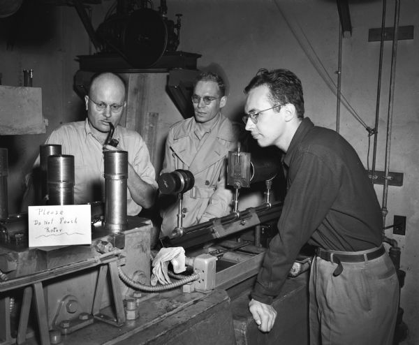 University of Wisconsin-Madison Chemistry Department open house. Three men are looking at equipment on laboratory table.