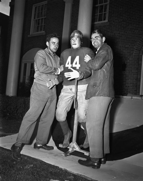 Homecoming decorations at the Delta Sigma Pi house, 132 Breese Terrace. Dennis Krahn, left, and Charles Krouse, right, set up a dummy with the numerals of Earl Girard, a famous Wisconsin football player.