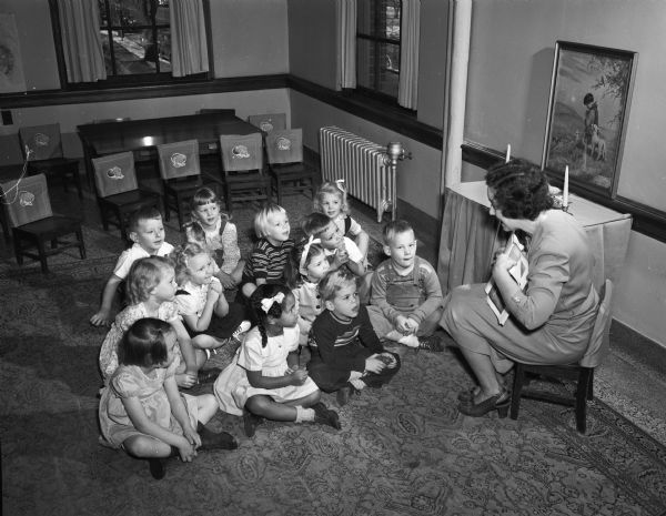 Sunday School Class at First Congregational Church, showing children sitting on the floor and a teacher sitting on a small chair.