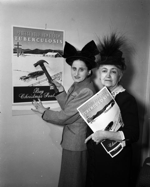 Mrs. Bernard (Edna) Heilprin and Mrs. William L.(Margaret) Dowling shown installing a Christmas Seal poster. They are members of the Madison Tuberculosis Association.