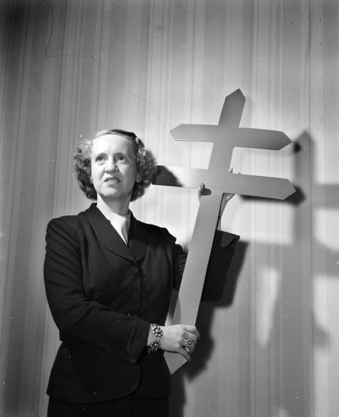 Miss Catherine Ahern, a member of the board of directors of the Madison Tuberculosis Association, holding a double-bar cross, the symbol of the association.