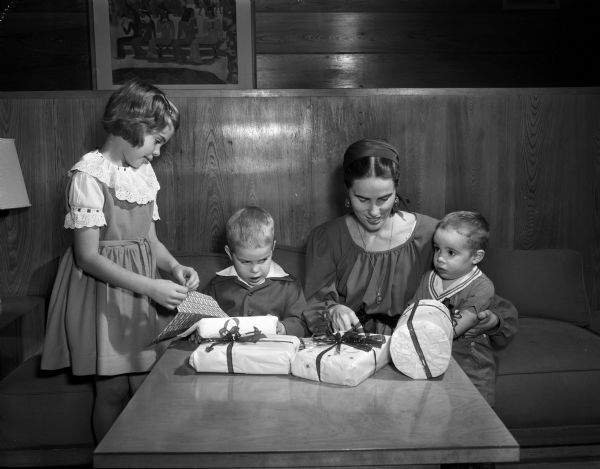 Mrs. James (Jane) Wilkie with her children, Sara, James, and William, shown wrapping presents using tuberculosis seals.