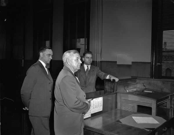 W.T. Evjue, editor of the <i>Capital Times</i>, pleading not guilty in Superior Court, charged for publishing the name of a 19-year-old rape victim. To the left is W. Wade Boardman, Evjue's attorney, to the right, District Attorney Edwin M. Wilkie, who signed the complaint. The judge is Roy H. Proctor.