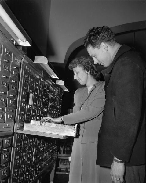 Helen Jansky, librarian, in charge of circulation, helping Elmer Brussow at the card catalog in the Madison Free Library, 206 North Carroll Street.