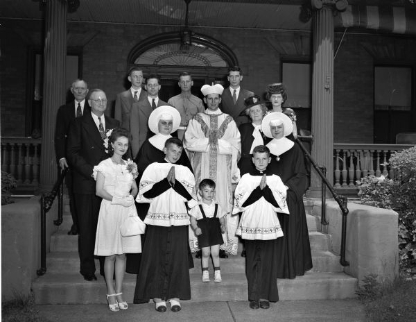 (Probably) Bishop Albert G. Meyer and his family, outside of St. Raphael's parish house, corner of Henry Street and 216 West Main Street.