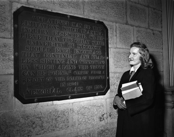 Female student looking at the University of Wisconsin-Madison "Sifting and Winnowing Plaque" located near the entrance to Bascom Hall.