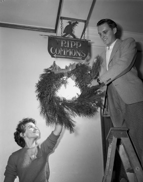 June Wandrey, Wautoma and Thorval Sautter, Wausau, hanging Christmas decorations at Memorial Union.