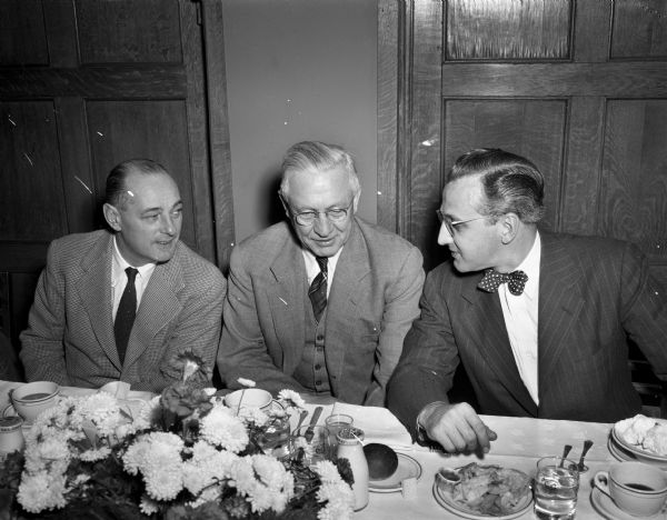 Roy Matson, editor of the Wisconsin State Journal, Governor Oscar Rennebohm, and Wisconsin football coach Harry Stuhldreher, left to right, seated at a banquet table at a dinner honoring the 1947 All-State high school football squad.