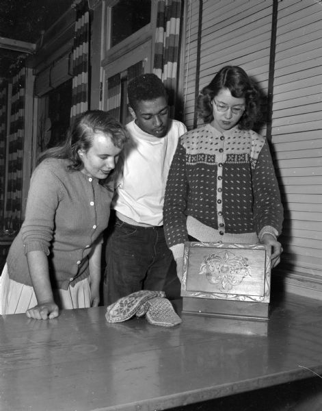 Left to right, Dorothy Kobs, Wisconsin High School student, James McDonald, Central High School student, and Amelia Brueckner, West High School student, looking at some of the things Amelia brought back from Norway where she spent the summer in the "Experiment in International Living" project.