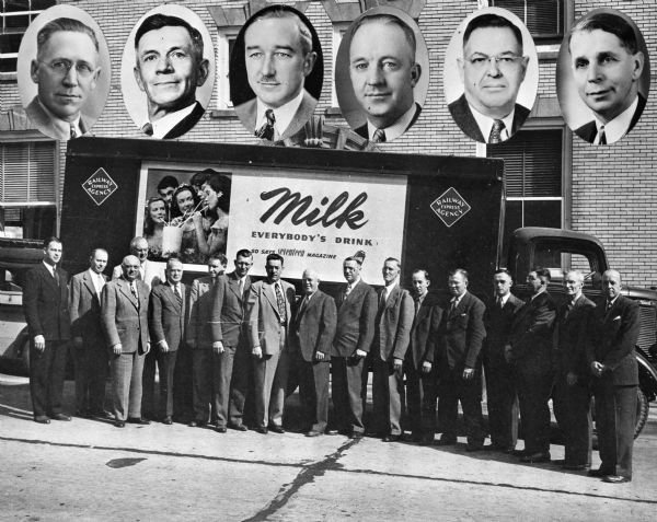 American Dairy Association truck with 17 men standing in front. Six faces of men are imposed over the building in the background above the truck.