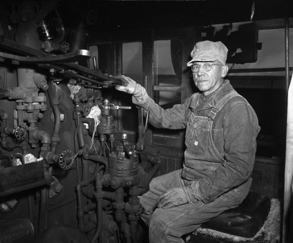 Portrait of Charles H. Thiede, 2218 Rusk Street, at the controls of a Chicago North Western Railroad steam engine as he starts his last run to Chicago after 41 years of employment.