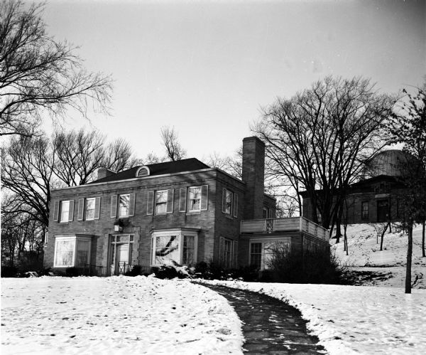 Exterior view of the University of Wisconsin-Madison Home Management house at 1430 Linden Drive. Seniors majoring in home economics were required to live for two weeks in the house. Washburn Observatory is on the hill in the background.