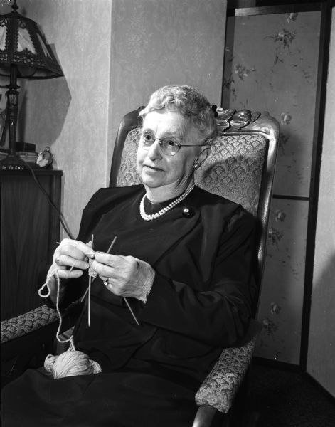 Portrait of Mrs. John L. (Mary) Gillin, 2211 Chamberlain Avenue, seated in a chair knitting for the State Journal Empty Stocking Club.