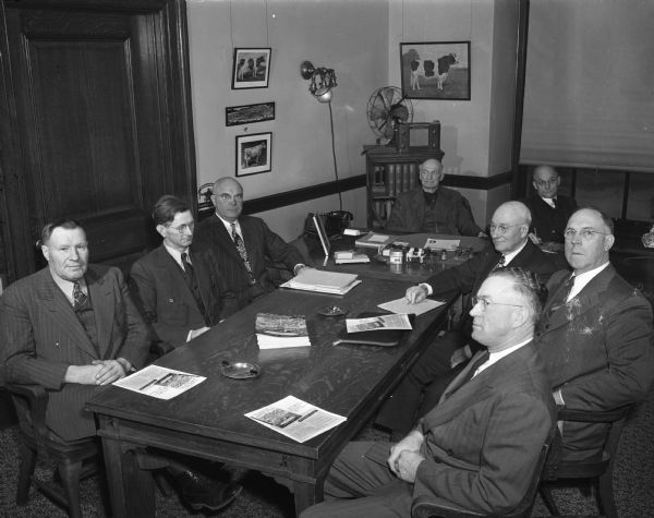 Group portrait of eight members of the Wisconsin Board of Agriculture  seated around a table.