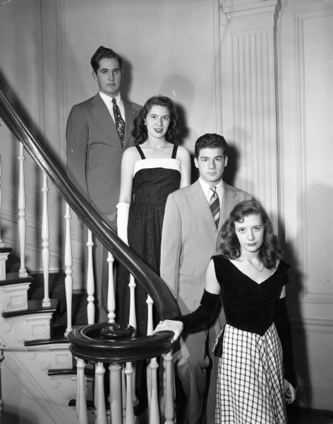 Four teenagers standing on the stairs at the Madison Club, 5 East Wilson Street, during a holiday formal party. Pictured left to right are: Kendall Glasier, and Marion Schiavo, both from Central High School; Larry Esser, Edgewood High School; Jeannine Yoakum, West High School.