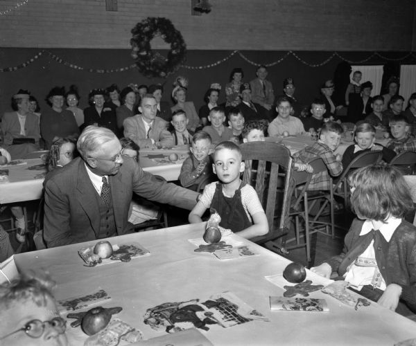 Governor Oscar Rennebohm sitting with a young boy at the Madison Shriners yule party at the Washington Orthopedic School, 545 West Dayton Street.