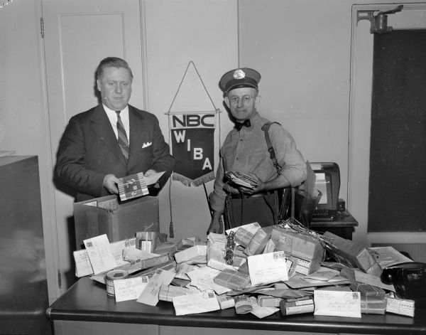 Mailman delivering Christmas letters and packages to a man at NBC - WIBA radio station.