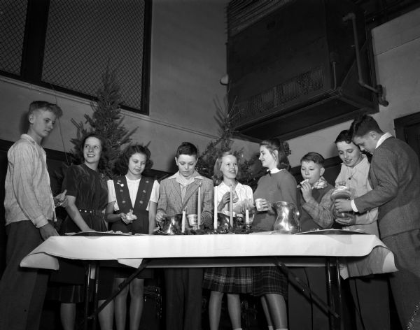 Nine young people gathered at the refreshment table at the annual neighborhood Christmas party given for all young people in Nakoma.  Pictured left to right: Roger Gaumnitz, Susan Dicky, Tom Williams, Virgina Roby, Susan Fisher, Dick Clarke, Thomas Fike, and Belden Mills.