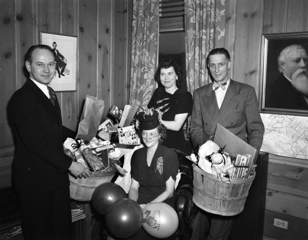 Members of the Madison Board of Realtors with three baskets of Christmas gifts for the Empty Stocking Club. Pictured left to right: Arnold Wake, chairman; Mrs. W.W. (Mildred) Atkinson, Mrs.(?) Wake, and Mr. Atkinson.