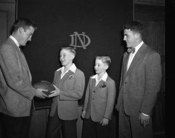 South Central Notre Dame Club dinner presentation of a football autographed by the 1947 Notre Dame football team to Billy Casey, St. Patrick Grade School student. Left to right: Terry Brennan, Billy Casey, Pat Casey, and Jim Brennan.