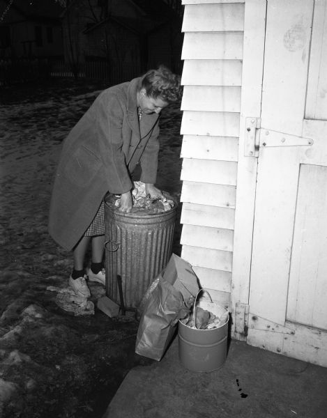 Mrs. John (Violet) Feeney demonstrating that she can not cram any more garbage into her garbage can because the city has not collected her garbage for nine days.