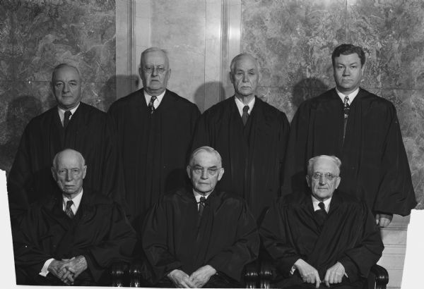 Group portrait of the Wisconsin State Supreme Court.  Seated left to right are: Chester A. Fowler; Chief Justice Marvin B. Rosenberry; and Oscar M. Fritz.  Standing left to right are:  Elmer E. Barlow; John D. Wickhem; Edward T. Fairchild; and newly elected Henry P. Hughes.